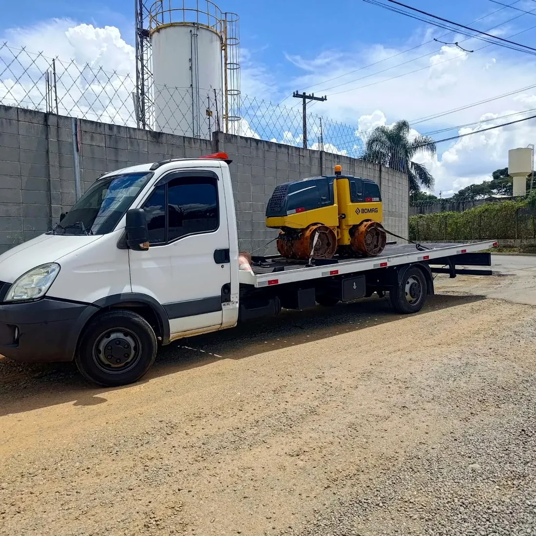 Rolo compactador amarelo sendo transportado por caminhão plataforma