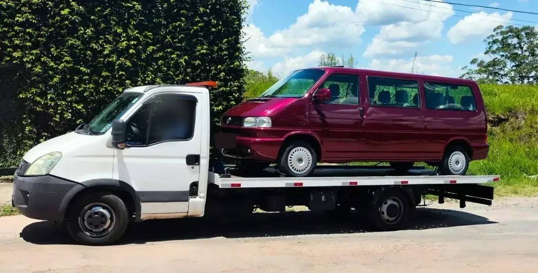 Van vinho sendo transportada em caminhão plataforma